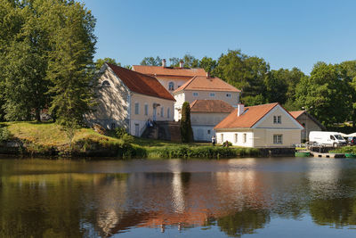 Houses by lake and buildings against sky