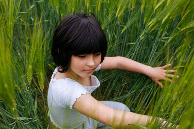 Portrait of smiling girl with dark hair sitting in the middle of grass