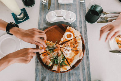 High angle view of hand holding pizza on table