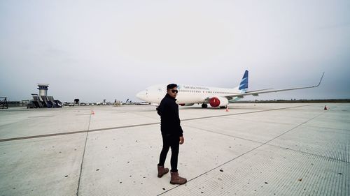 Woman standing on airport runway against sky