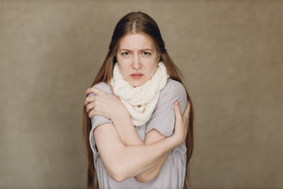 Portrait of young woman standing against wall