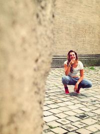 Portrait of young woman sitting on wall