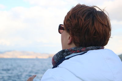 Rear view of woman in sunglasses against sky during winter