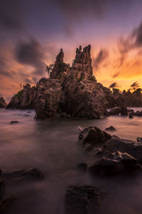 Rock formation on beach against sky during sunset