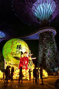 People on illuminated tree at night