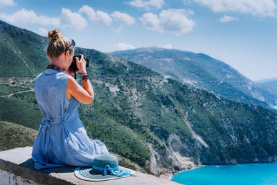 Woman photographing on mountain against sky