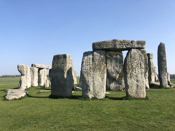 Stone structure on field against clear sky