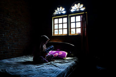 Man relaxing on bed against window in building