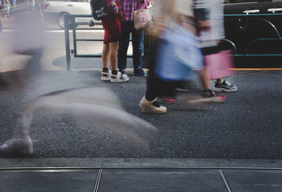 Low section of people walking on road in city