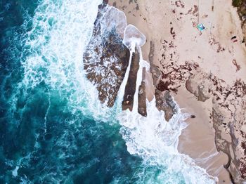 Aerial view of sea waves flowing on shore at beach