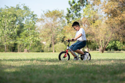 Side view of boy riding bicycle on grass