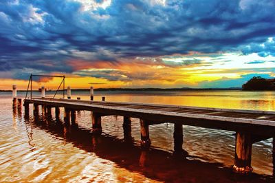 Pier over sea against sky during sunset