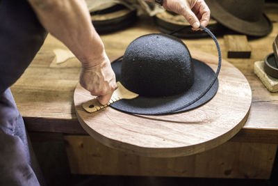 Midsection of man making hat on table in workshop