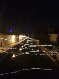 Illuminated road against sky at night