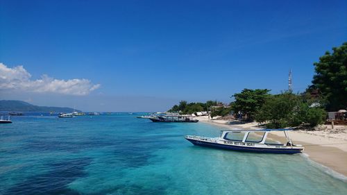 Boats moored on sea against blue sky