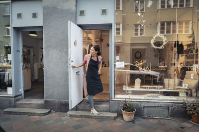 Female entrepreneur peeking out while standing at doorway of design studio