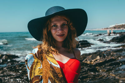 Portrait of smiling woman standing at beach against sky