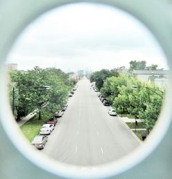 Road amidst trees against sky in city