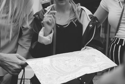 Midsection of woman discussing map with friends