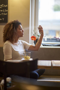 Woman spraying on her face while sitting at restaurant