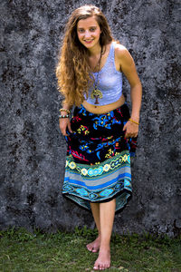 Portrait of smiling young woman standing against wall