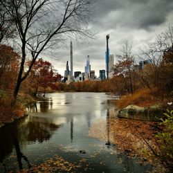 River by buildings against sky during autumn