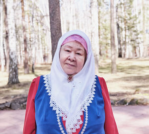 Half-length portrait of an elderly muslim woman in traditional festive dress looking at the camera