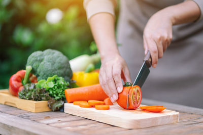 Midsection of man with vegetables on cutting board