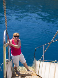 Woman in sunglasses standing on steps against lake