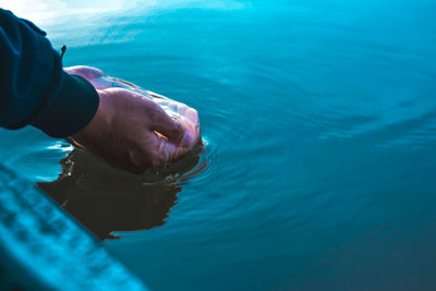 Cropped hand of person collecting water in sea