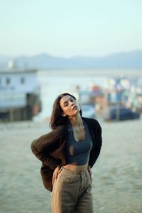 Portrait of young woman standing against sea