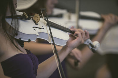Midsection of women playing violins at music concert