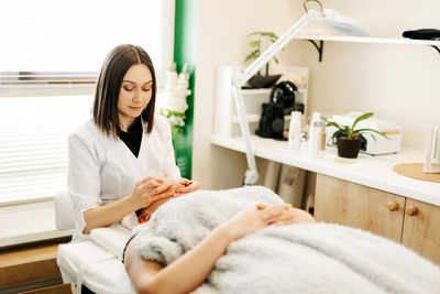 A cosmetologist massages the skin of a young woman with a gouache scraper. facial massage