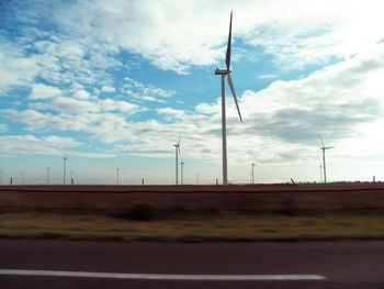 Wind turbines on field against sky
