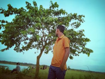 Man standing by tree against sky