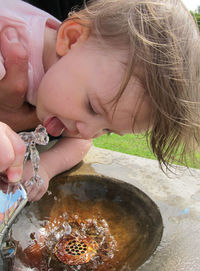 Close-up of girl drinking from water fountain