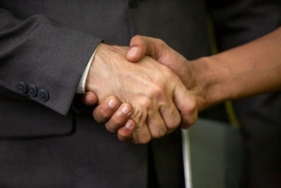 Midsection of man shaking hand with colleague