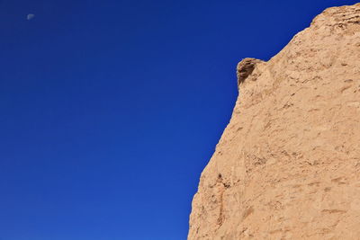 Low angle view of rock formation against clear blue sky