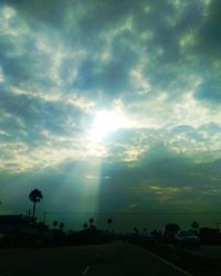 Road by silhouette city against sky during sunset