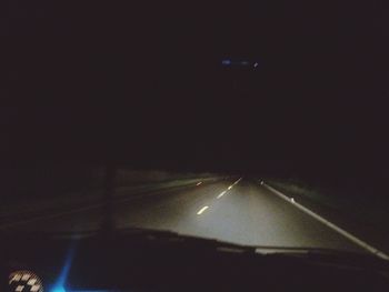 Illuminated road against sky at night