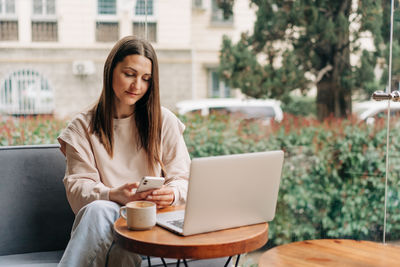 Young woman using laptop while sitting on chair