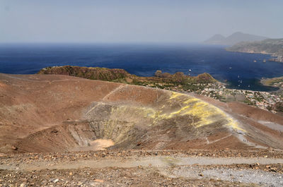 Barren landscape against calm blue sea