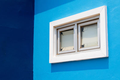 Low angle view of window on blue wall of building