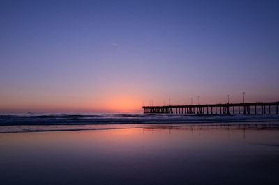 Silhouette santa monica pier over sea during sunset