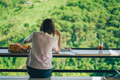 Rear view of woman sitting on table