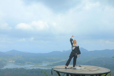 Woman standing on tower against cloudy sky