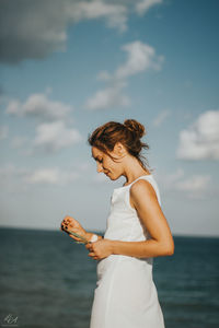 Side view of woman standing against sea