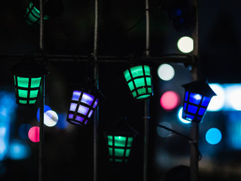 Low angle view of illuminated lighting equipment hanging at night