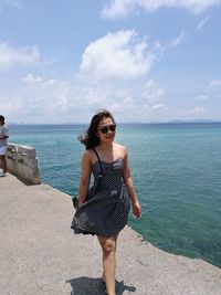 Portrait of woman standing by sea against sky