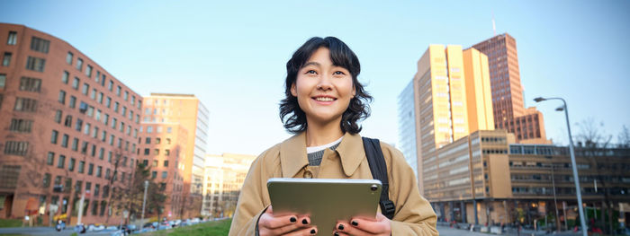 Portrait of young woman using mobile phone in city